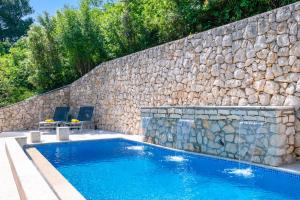 a swimming pool next to a stone wall at Villa Pia by Briskva in Brseč +34 photos