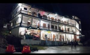 a large white building with people standing in front of it at Hotel Him darshan in Madheso
