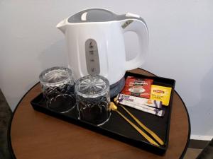 a table with a tea kettle and two glasses on it at Hotel O HNR INN in Kuala Terengganu