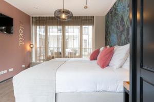 a bedroom with a large white bed with red pillows at Juuls Domburg in Domburg
