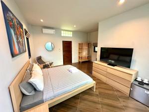a bedroom with a bed and a flat screen tv at Acqua Rooms & Living in Koh Samui