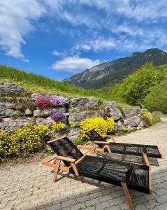 a bench and a chair sitting next to a stone wall at Lauchlehen in Bischofswiesen