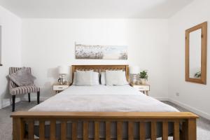 a bedroom with a bed and a mirror and a chair at Aval Dor Barn, Hot Tub, Pet Friendly in Ludgvan +24 photos