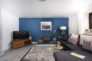 a living room with a black couch and a blue wall at Aval Dor Barn, Hot Tub, Pet Friendly in Ludgvan