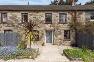 an old stone house with a fence in front of it at Aval Dor Barn, Hot Tub, Pet Friendly in Ludgvan