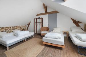 a attic room with two beds and a chair at Bulle de Douceur avec Spa in Vallons-de-l'Erdre +5 photos