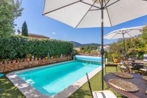 a swimming pool with a table and an umbrella at Gite Chez Sophie in Roquebrune-sur-Argens +15 photos
