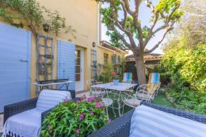 a patio with a table and chairs and a tree at Gite Chez Sophie in Roquebrune-sur-Argens