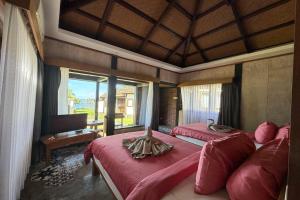 a bedroom with two beds with red sheets and a piano at Hi Blue Bali Melasti Dive Resort in Karangasem