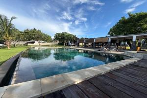 a swimming pool with a wooden deck next to a building at Hi Blue Bali Melasti Dive Resort in Karangasem