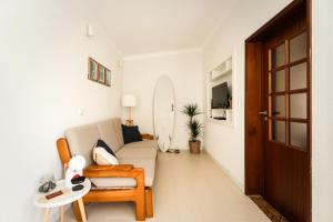 a living room with a couch and a surfboard at Casa da Areia - by RowdHouses - Private Beach Access in Praia da Barra