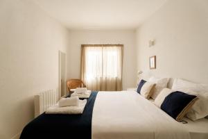 a large white bed in a room with a window at Casa da Areia - by RowdHouses - Private Beach Access in Praia da Barra