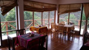 una sala da pranzo con tavoli, sedie e ampie finestre di El Encanto Sorata a Sorata