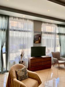 a living room with a tv and a couch and windows at Isidora Hotel in Agia Marina Aegina