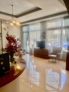 a living room with a television and a table and chairs at Isidora Hotel in Agia Marina Aegina