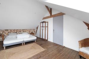 a white bedroom with a bed and a chair at Bulle de Douceur avec Spa in Vallons-de-l'Erdre