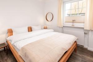 a bedroom with a large white bed with a window at Ant Diekskant in Juist