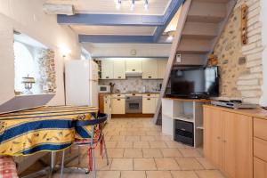 a kitchen with a table and a tv in a room at La Petite Maison in Puimoisson