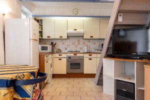 a small kitchen with white cabinets and a flat screen tv at La Petite Maison in Puimoisson +22 photos
