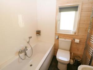 a bathroom with a tub and a toilet and a window at Dovestone Luxury Lodges sleeps 6 - pet free in Oldham +22 photos