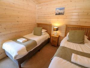 a bedroom with two beds in a log cabin at Dovestone Luxury Lodges sleeps 6 - pet free in Oldham