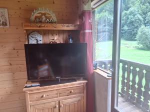 a large flat screen tv sitting on a dresser next to a window at Duplex au calme vue montagne in Abondance