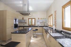 a large kitchen with black counter tops and a sink at Villa Valentina by Algarve Holidays in Almancil