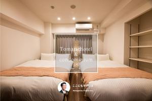 a woman standing between two beds in a room at Tomariehotel & condominium in Fukuoka