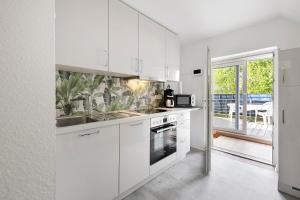 a white kitchen with white cabinets and a balcony at Süße kleine Wohnung in Eggstedt
