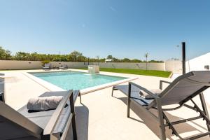 a patio with a pool and two chairs and a swimming pool at Villa Antonio ZadarVillas in Nin