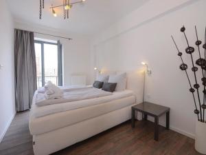 a white bedroom with a bed and a table at Ohlerich Speicher App_ 02 in Wismar +9 photos