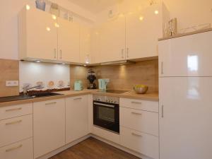 a white kitchen with white cabinets and a refrigerator at Ohlerich Speicher App_ 02 in Wismar