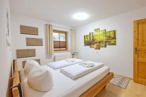 a white bedroom with two beds and a window at Freigeist in Nesselwang