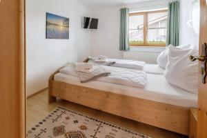 a bedroom with a bed with white sheets and a window at Freigeist in Nesselwang +16 photos