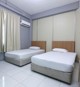 two twin beds in a room with a window at Hotel O D'noor in Kota Bharu
