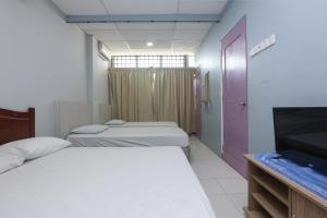 a room with two beds and a flat screen tv at Hotel O D'noor in Kota Bharu