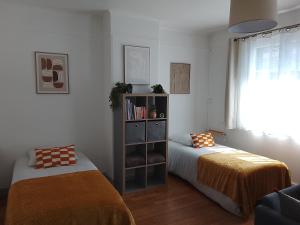 a bedroom with two beds and a book shelf at l'Aiglon in LʼAigle