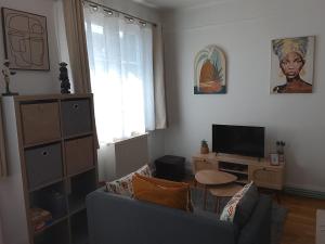 a living room with a couch and a tv at l'Aiglon in LʼAigle