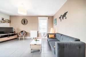a living room with a couch and a tv at Le Cocon in Thonon-les-Bains