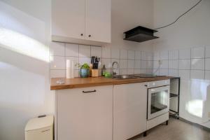 a small kitchen with white cabinets and a sink at Zentral & ruhig - Stadt, Elbe und Natur nebenan in Magdeburg