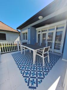 a patio with a table and a bench in front of a house at LelleBlue Vendégház in Balatonlelle