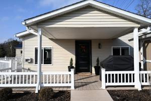 a white house with a porch and a white fence at Pondside Abode in Dundee
