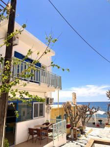 a house with a balcony and a table on the beach at Maria Mare in Myrtos