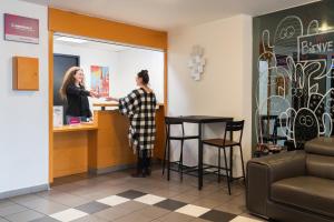 two women are standing at a counter in a store at The Originals Residence Appart'Hôtel Lauréades Clermont-Ferrand Centre Jaude in Clermont-Ferrand