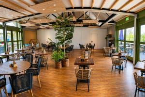 a restaurant with tables and chairs and windows at Prins Chalets Hoogersmilde Drenthe in Hoogersmilde