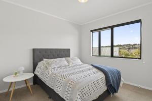 a white bedroom with a bed and a window at Welcome Bay Stay in Tauranga