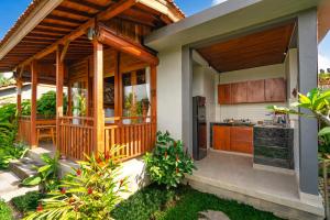 a house with a large wooden porch with a kitchen at Shankara D'Uma in Ubud