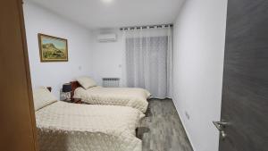 two beds in a room with white walls at Spacious accommodation with city views in Haï Khemisti