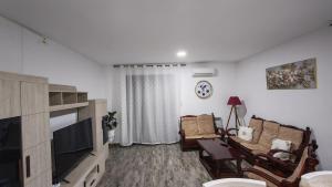 a living room with two chairs and a flat screen tv at Spacious accommodation with city views in Haï Khemisti