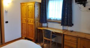 a bedroom with a desk and a window and a chair at Hotel Giardino in Bormio